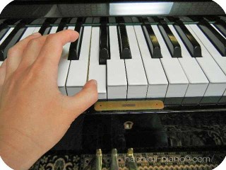 アップライトピアノの真ん中のドを左手で弾く。